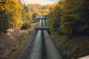 ​Large pipelines running through a forested landscape representing oil and gas infrastructure